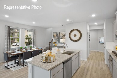 Kitchen featuring an island with sink, light hardwood / wood-style floors, light stone countertops, and stainless steel dishwasher