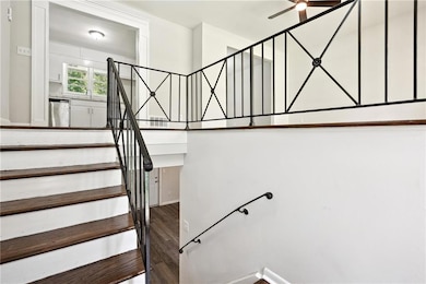 Stairway with wood finished floors and ceiling fan