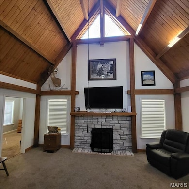 Living area with a wood ceiling with exposed beams, high vaulted ceiling, carpet flooring, healthy amount of natural light, and a stone fireplace