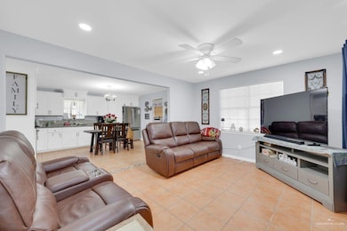 Living room featuring light tile patterned flooring, recessed lighting, a ceiling fan, and a chandelier