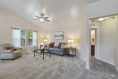 Carpeted living area featuring a ceiling fan and vaulted ceiling