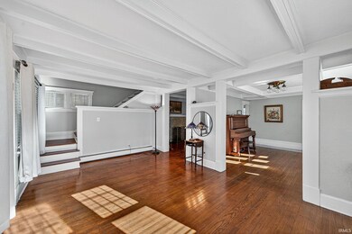 Living area featuring dark wood-type flooring, stairs, and beamed ceiling