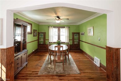 Hardwood floored dining room featuring crown molding, ceiling fan and fantastic original built in cabinetry.