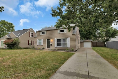 View of front of house featuring driveway, a garage, and an outbuilding