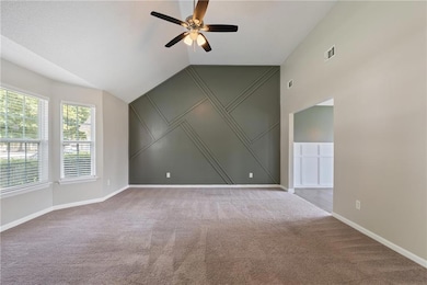 Living room with lofted ceiling, light carpet, a ceiling fan, and a decorative wall