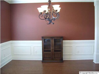 Formal dining room with hardwood floors, wainscoting, crown molding, columns and chandelier.