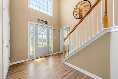 Entryway featuring healthy amount of natural light, wood finished floors, a towering ceiling, stairs, and baseboards