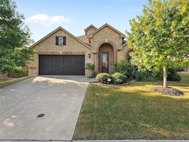 Country home with brick siding, stone siding, concrete driveway, a front lawn, and a garage