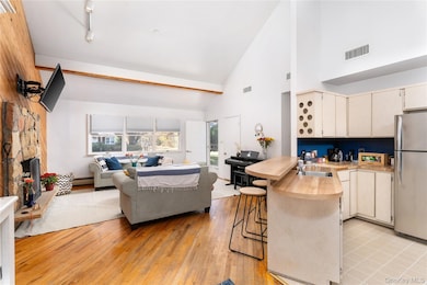 Kitchen featuring open floor plan, high vaulted ceiling, a kitchen bar, light countertops, and freestanding refrigerator