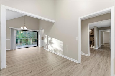 Unfurnished room featuring a towering ceiling, a chandelier, and light wood-type flooring