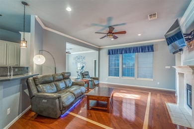 Living area with a ceiling fan, hardwood / wood-style flooring, ornamental molding, a tile fireplace, and recessed lighting