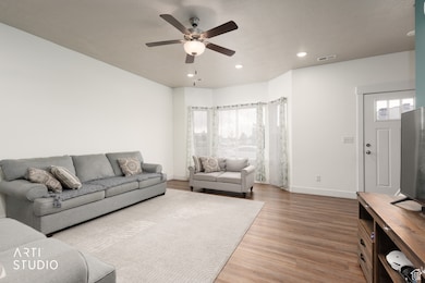 Living room with light wood finished floors, recessed lighting, healthy amount of natural light, and a ceiling fan