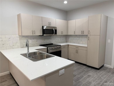 Kitchen with light wood-type flooring, kitchen peninsula, sink, and appliances with stainless steel finishes