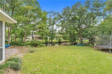 View of grassy yard featuring a trampoline and a water view