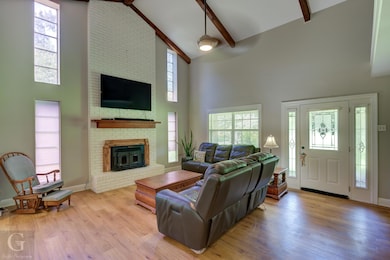 Living room featuring beamed ceiling, a brick fire