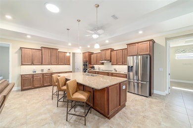Beautiful gourmet kitchen showcasing stone countertops, under-cabinet lighting, soft-close cabinetry, added island storage, and sleek stainless steel appliances.