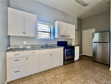 Kitchen featuring white cabinetry, under cabinet range hood, dark stone counters, appliances with stainless steel finishes, and a sink