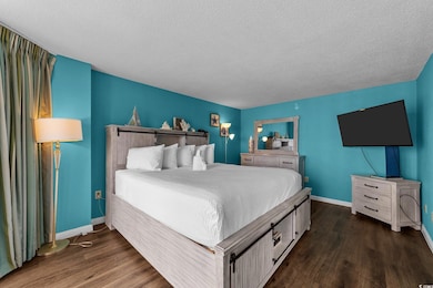 Bedroom featuring wood finished floors, a textured ceiling, and baseboards