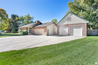 View of front of home with a garage, a chimney, driveway, and brick siding