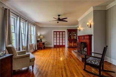 Living area featuring hardwood / wood-style floors, a ceiling fan, a brick fireplace, and crown molding