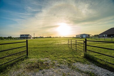 Gate at dusk featuring a lawn and a rural view