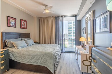 Bedroom featuring a wall of windows, light wood finished floors, access to outside, multiple windows, and a ceiling fan