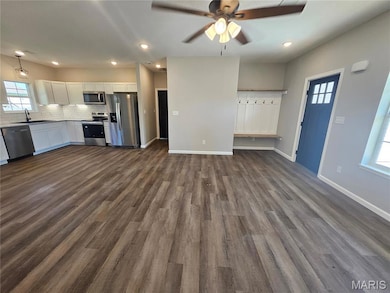 Unfurnished living room with healthy amount of natural light, a ceiling fan, recessed lighting, and dark wood-style floors