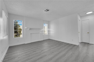 Unfurnished room featuring healthy amount of natural light, light wood-style flooring, and a textured ceiling