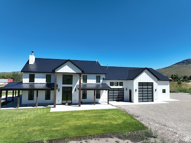 Modern farmhouse featuring a standing seam roof, board and batten siding, a metal roof, a front yard, and an attached garage