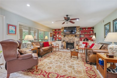 Living room with a ceiling fan, a fireplace, ornam
