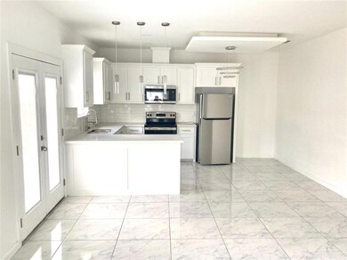 Kitchen with appliances with stainless steel finishes, light marble finish floors, light countertops, a peninsula, and backsplash