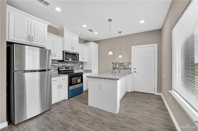Kitchen with appliances with stainless steel finishes, white cabinetry, decorative backsplash, light stone countertops, and recessed lighting