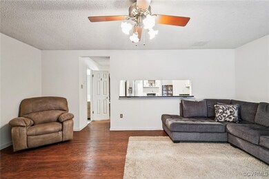 Living area with dark wood finished floors, ceiling fan, and a textured ceiling