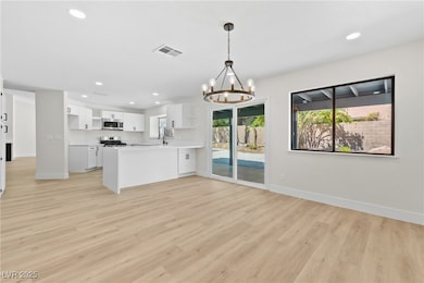 Kitchen featuring open shelves, white cabinets, a peninsula, light wood-type flooring, and a chandelier