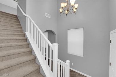 Staircase featuring a chandelier, a high ceiling,
