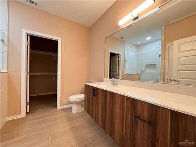 Bathroom featuring wood-type flooring, vanity with extensive cabinet space, and toilet