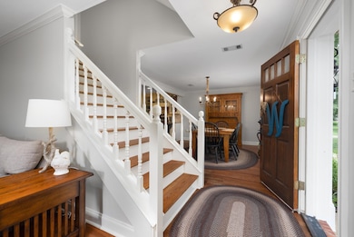 Foyer with stairway, wood finished floors, a chandelier, crown molding, and baseboards