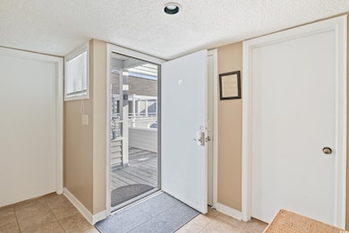 Foyer entrance featuring a textured ceiling and li