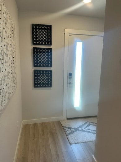 Doorway featuring wood finished floors and baseboa