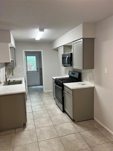 Kitchen with stove, backsplash, gray cabinets, an