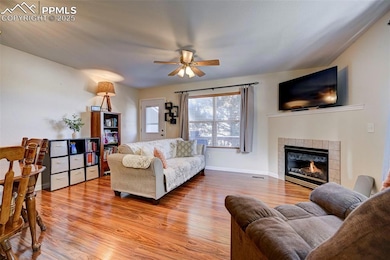 Living room featuring a tiled fireplace, ceiling f