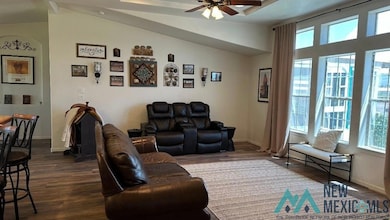 Living room with dark wood finished floors, vaulted ceiling, and ceiling fan