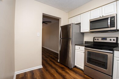 Kitchen featuring baseboards, white cabinetry, dar
