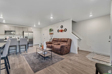 Living area featuring light wood-style flooring, recessed lighting, and stairway
