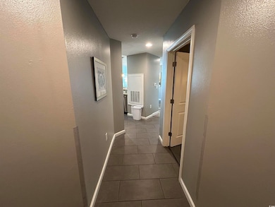 Hallway featuring baseboards and dark tile pattern