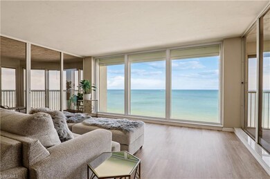 Living room with expansive windows, a view of the Gulf of Mexico, and light hardwood / wood-style floors