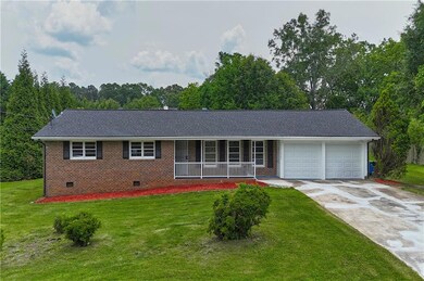 Ranch-style house with crawl space, an attached garage, a porch, a front lawn, and driveway