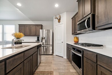 Living room with ceiling fan with notable chandelier, hardwood / wood-style flooring, a fireplace, and lofted ceiling