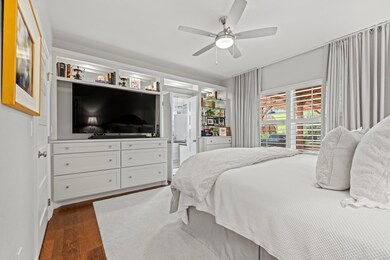 Bedroom with ceiling fan and dark wood finished f