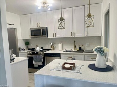 Kitchen featuring white cabinetry, tasteful backsplash, a sink, light stone counters, and appliances with stainless steel finishes